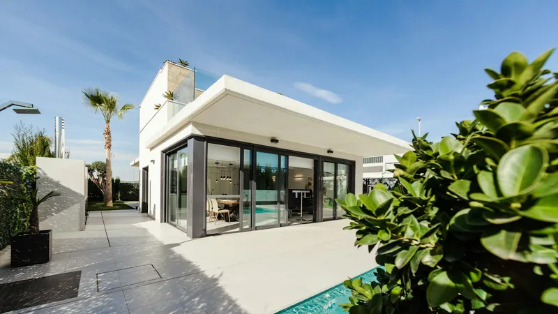 Florida home with floor to ceiling sliding glass doors beside a palm tree and pool